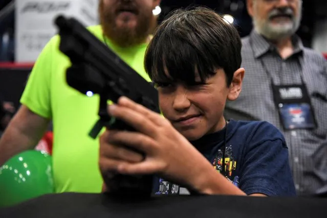 A child engages in virtual target practice as attendees try out the guns on display at the National Rifle Association (NRA) annual convention in Houston, Texas, U.S. May 28, 2022. (Photo by Callaghan O'Hare/Reuters)