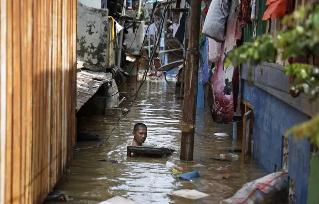 A man swims in flood water in a low-income neighborhood in Jakarta, Indonesia, Thursday, January 2, 2020. Severe flooding in the capital as residents celebrated the new year has killed scores of people and displaced tens of thousands, the country's disaster management agency said. (Photo by Dita Alangkara/AP Photo)