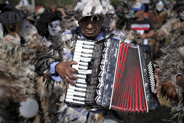 A musician dressed in a feathered costume pays tribute to Saint Francisco Solano for a fulfilled prayer during a procession in his honor in Emboscada, Paraguay, Monday, July 24, 2023. Legend has it that while lying on his death bed in a Peruvian convent birds perched on Solano's window and would sing to him, inspiring his followers to dress in bird costumes and he became known as the saint of the birds. (Photo by Jorge Saenz/AP Photo)