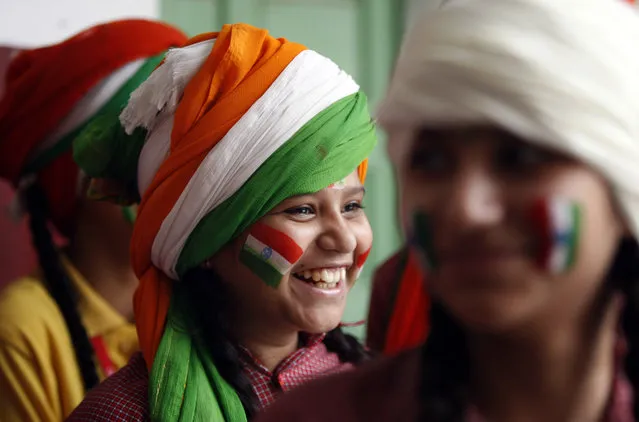 A girl, with her face painted in tricolor Indian flag, smiles as she waits to perform during celebrations in a school on the eve of Independence Day in Jammu, India, Friday, August 14, 2015. (Photo by Channi Anand/AP Photo)