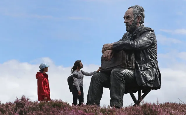 Visitors look at The Seated Man, a 3 meter sculpture by Sean Henry, near Westerdale in the North York Moors National Park, Castleton Rigg, UK on August 6, 2017. (Photo by Owen Humphreys/PA Wire)