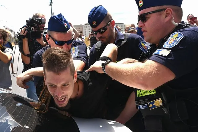 Hungarian police arrest a demonstrator as several hundreds block Margaret Bridge (Margit Bridge), one of the most frequented bridges of the Hungarian capital, to protest against the Orban government's proposed amendment to taxation legislation in Budapest on July 12, 2022. Hundreds protested on July 12 against the proposed amendment, which is expected to be approved in parliament although small entrepreneurs – already struggling with inflation – say it will drastically increase their tax burden. (Photo by Attila Kisbenedek/AFP Photo)