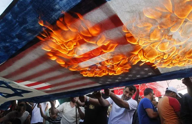 Lebanese and Palestinian protesters set fire to U.S. and Israeli flags during a demonstration to denounce Israeli air strikes on the Gaza strip, in Lebanon's southern port-city of Sidon July 10, 2014. At least 77 Palestinians, most of them civilians, have been killed in Israel's Gaza offensive, Palestinian officials said on Thursday, and militants kept up rocket attacks on Tel Aviv, Jerusalem and other cities in warfare showing no signs of ending soon. (Photo by Ali Hashisho/Reuters)