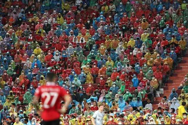 Fans in Thailand watch the game in the rain dressed in coloured ponchos during the preseason friendly match between Liverpool and Manchester United at Rajamangala Stadium on July 12, 2022 in Bangkok, Thailand. (Photo by Matthew Ashton – AMA/Getty Images)