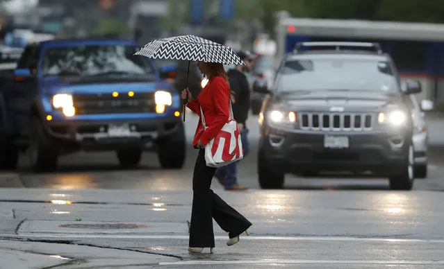 A pedestrian seeks cover under an umbrella while crossing the street as heavy rains swamp the city core late Monday, August 7, 2017, in Denver. (Photo by David Zalubowski/AP Photo)