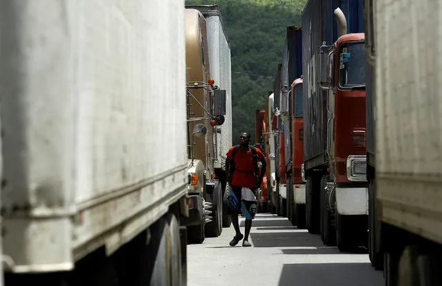 An African migrant stranded in Costa Rica walks near parked trucks at the border between Costa Rica and Nicaragua, in Penas Blancas, Costa Rica, July 14, 2016. (Photo by Juan Carlos Ulate/Reuters)