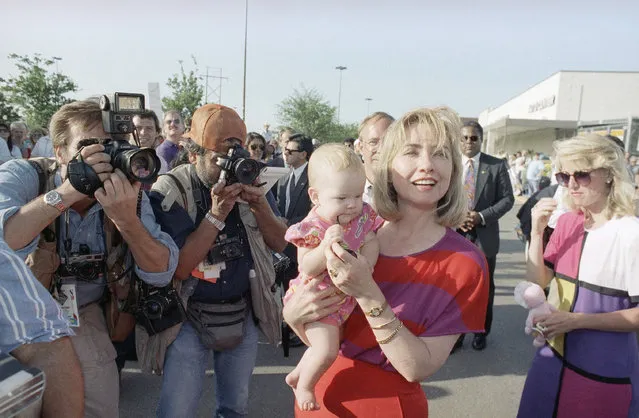 Hillary Rodham Clinton carries 6-month-old Murphy McCollough past news photographers during an impromptu stop in Georgetown, Texas on Thursday, August 27, 1992. The Democratic presidential and vice-presidential candidates and their wives are on a two-day bus tour through Texas. (Photo by Stephan Savoia/AP Photo)