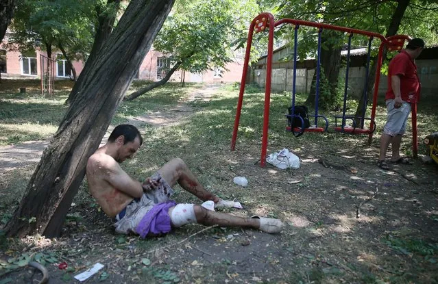 A wounded man in a childrens playground after a mortar attack by the Ukrainian army of the center of Donetsk, Ukraine, 14 August 2014. Reports state that ten local people where wounded and one killed after the mortar attack. (Photo by Sergei Ilnitsky/EPA)