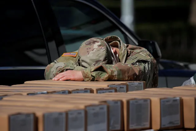 A U.S. Army National Guard member rests on boxes of preferred meals that were being distributed free to residents in the East Harlem section of Manhattan during the outbreak of the coronavirus disease (COVID-19) in New York City, New York, U.S., April 1, 2020. (Photo by Brendan Mcdermid/Reuters)