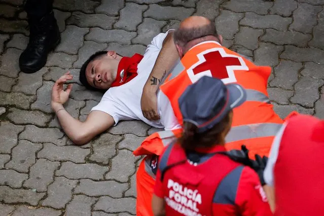 A reveller is helped by medical staff during the running of the bulls at the San Fermin festival in Pamplona, Spain, July 14, 2022. (Photo by Juan Medina/Reuters)