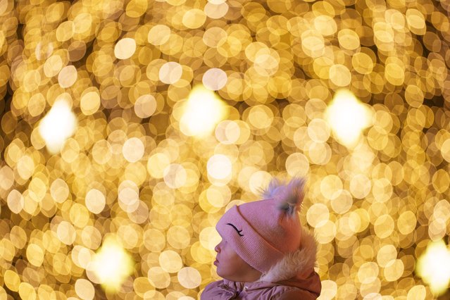 A child looks at light installations while being carried on an adult's shoulders at a Christmas fair in Bucharest, Romania, Saturday, December 14, 2024. (Photo by Andreea Alexandru/AP Photo)