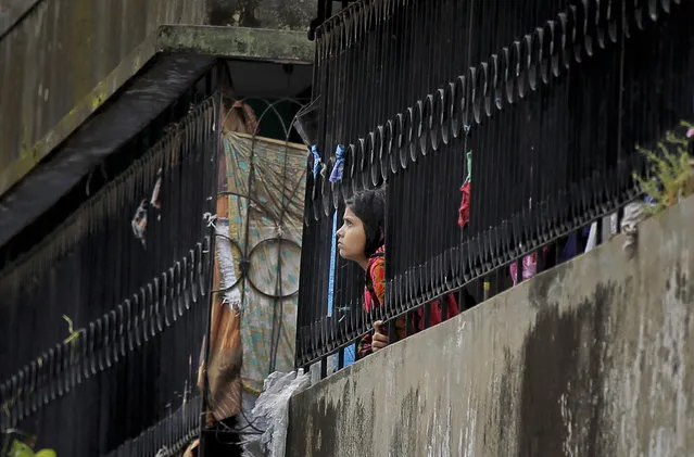 A Bangladeshi girl watches from a nearby building after a five-story building was raided by police in Dhaka, Bangladesh, Tuesday, July 26, 2016. (Photo by AP Photo)