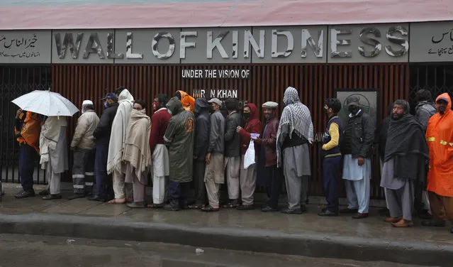 Daily wage workers left jobless due to travel restrictions aimed at containing the coronavirus, wait their turn to receive free food in Rawalpindi, Pakistan, Tuesday, March 24, 2020. According to the World Health Organization, most people recover from the virus in about two to six weeks, depending on the severity of the illness. (Photo by Anjum Naveed/AP Photo)