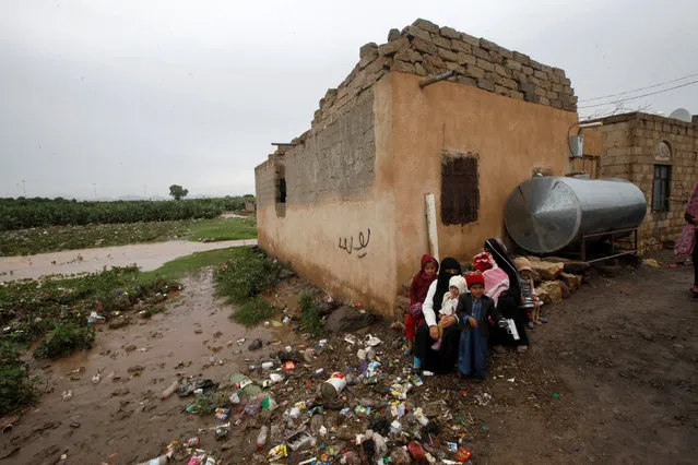 A family sits outside their flooded house on the outskirts of Sanaa, Yemen, July 31, 2016. (Photo by Mohamed al-Sayaghi/Reuters)