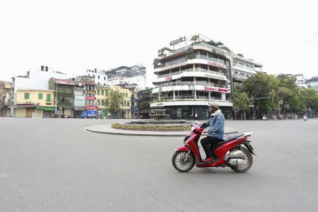 A motorcyclist drives on a quiet street in Hanoi, Vietnam, Wednesday, April 1, 2020. Vietnam on Wednesday starts two weeks of social distancing to contain the spread of COVID-19. (Photo by Hau Dinh/AP Photo)