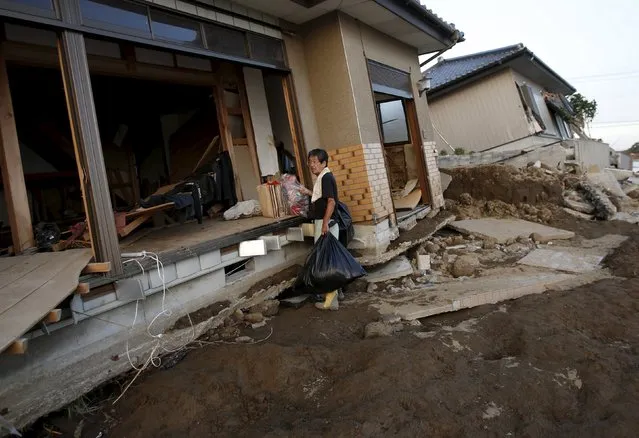 A local resident collects personal belongings from his destroyed house at a residential area flooded by the Kinugawa river, caused by typhoon Etau, in Joso, Ibaraki prefecture, Japan, September 11, 2015. (Photo by Issei Kato/Reuters)