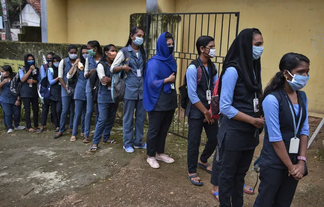 School children wearing masks line up to get their hands sanitized and temperatures checked as they arrive to appear for state board examination during the coronavirus pandemic in Kochi, Kerala state, India, Tuesday, May 26, 2020. (Photo by R.S. Iyer/AP Photo)