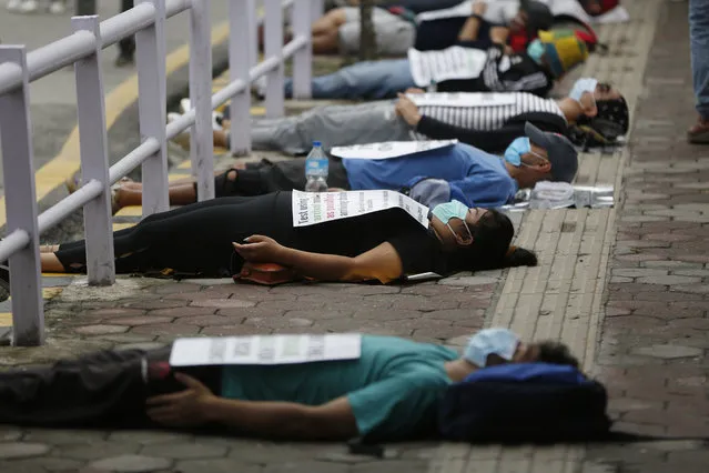 Protesters lie on the ground demanding better handling of the COVID-19 pandemic in Kathmandu, Nepal, Saturday, June 20, 2020. Hundreds participated demanding increased testing and protesting alleged corruption by government officials while purchasing equipment and testing kits. (Photo by Niranjan Shrestha/AP Photo)