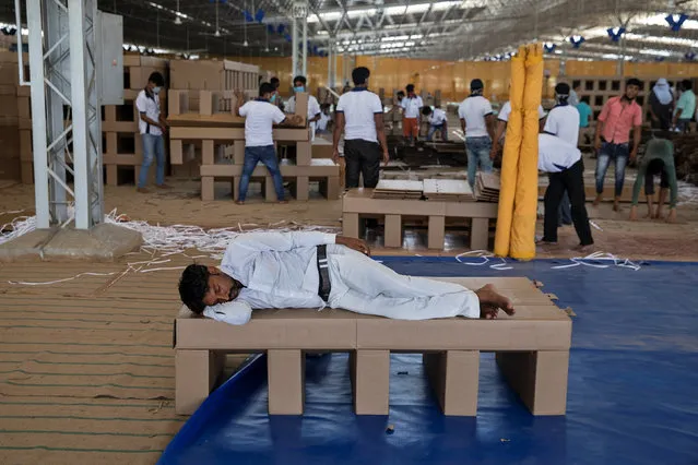 A worker rests as others make disposable beds made out of cardboard at the campus of Radha Soami Satsang Beas, a spiritual organization, where a coronavirus disease (COVID-19) care centre has been constructed for the patients amidst the spread of the disease, in New Delhi, India, June 25, 2020. (Photo by Danish Siddiqui/Reuters)