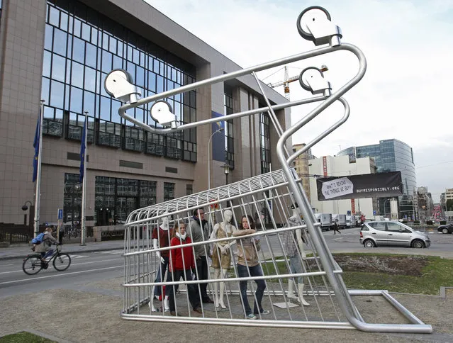 Workers are trapped under an upside-down shopping trolley placed outside the European Union headquarters in Brussels October 19, 2009 as part of an ad campaign to raise awareness about modern slave labor. (Photo by Thierry Roge/Reuters)