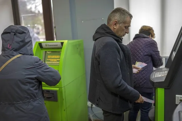 Residents operate ATMs inside a bank branch in Kherson, southern Ukraine, Monday, November 21, 2022. (Photo by Bernat Armangue/AP Photo)