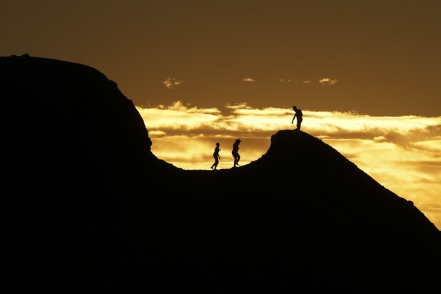 People are silhouetted against the sunset at Papago Park in Phoenix, March 1, 2025. (Photo by Lindsey Wasson/AP Photo)