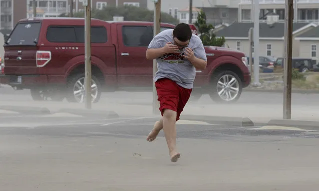 Eli White covers his face from the blowing sand in Nags Head, N.C., Saturday, September 3, 2016 as the tail of Tropical Storm Hermine passes the Outer Banks.  Hermine lost hurricane strength over land but was intensifying Saturday along the Atlantic Coast, threatening heavy rain, wind and storm surges on its northward march. (Photo by Tom Copeland/AP Photo)