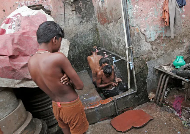 A boy waits for his turn to take a bath at roadside municipal taps on a cold winter morning in the old quarters of Delhi, India, December 14, 2017. (Photo by Adnan Abidi/Reuters)