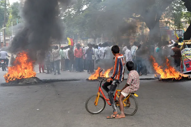 Indian children look on as activists burn tyres and material to blockade traffic on a major connecting road during a statewide strike in Bangalore on September 9, 2016. Agitation in the southern Indian state of Karnataka has been increasing since the recent Supreme Court order to the state to release of 15,000 cusecs of water from the River Cauvery each day to the neighbouring state of Tamil Nadu. Karnataka is facing an acute shortage of water in its reservoirs, and rivers as the state has only received subpar rainfall in the catchment areas leading to protests by farmers and pro-Kannada organisations refusing to share water with its neighbouring state. (Photo by Manjunath Kiran/AFP Photo)