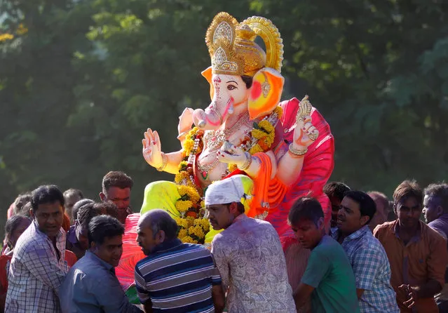 Devotees carry an idol of the Hindu god Ganesh, the deity of prosperity, for its immersion in the Sabarmati river during the 10-day-long Ganesh Chaturthi festival in Ahmedabad, India, September 11, 2016. (Photo by Amit Dave/Reuters)