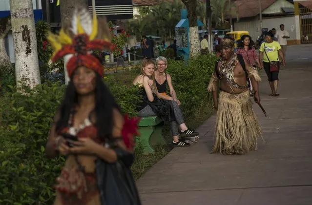 Tourists look at Amazonian indigenous people as they walk in downtown Puerto Maldonado, Madre de Dios province, Peru, Thursday, January 18, 2018, one day ahead of Pope Francis' arrival to Peru's Amazon. (Photo by Rodrigo Abd/AP Photo)