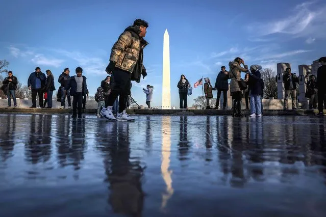People play on the frozen Reflecting Pool on the National Mall near the Washington Monument (rear) on December 28, 2022 in Washington, DC. (Photo by Oliver Contreras/AFP Photo)