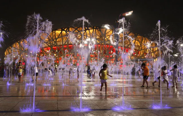 Children play in water fountains next to the National Stadium, also known as the Bird's Nest, during the Beijing 2008 Olympic Games. (Photo by Eric Gaillard/Reuters)