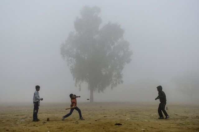 Children play a traditional South Asian game called “Gilli-Danda” (stick and peg) amid dense fog on a cold winter morning at a ground in Jalandhar, India on January 4, 2025. (Photo by Shammi Mehra/AFP Photo)
