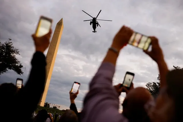 People take pictures of Marine One with U.S. President Donald Trump as it flies to the White House after the president underwent treatment for the coronavirus disease (COVID-19), in Washington, U.S., October 5, 2020. (Photo by Carlos Barria/Reuters)