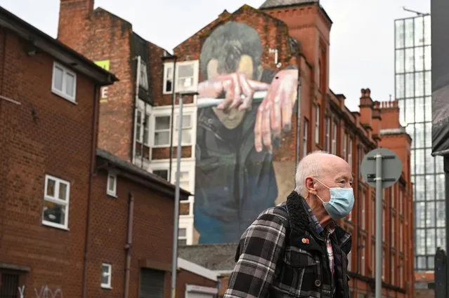 A man wearing a facemask walks past a mural painted as part of the Cities of Hope festival in 2016 and highlighting the effects of mental health, in Ancoats, northern Manchester on October 16, 2020, as the number of cases of the novel coronavirus COVID-19 rises. The government on Thursday announced more stringent measures but as ministers tightened the screw on social interaction to cut close-contact transmission, they sparked a furious row with leaders in northwest England, where infection rates are highest. Greater Manchester Mayor Andy Burnham accused the government of being “willing to sacrifice jobs and businesses here to try and save them elsewhere”. (Photo by Oli Scarff/AFP Photo)