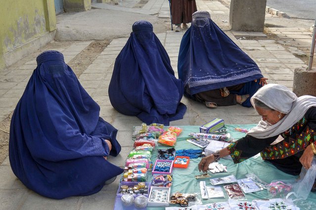 Afghan burqa-clad women shop for beauty accessories at a roadside stall in Kandahar province on August 18, 2025. (Photo by Sanaullah Seiam/AFP Photo)