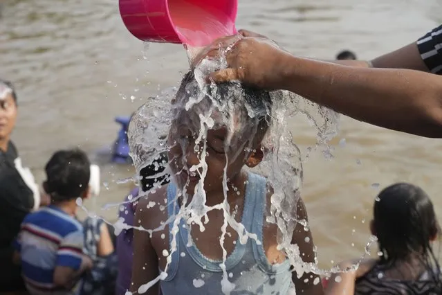 A woman is helped to take shower in the Cisadane River, ahead the holy fasting month of Ramadan in Tangerang, Indonesia, Tuesday, March 21, 2023. Muslims followed local tradition to wash in the river to symbolically cleanse their soul prior to entering the holiest month in Islamic calendar. (Photo by Tatan Syuflana/AP Photo)