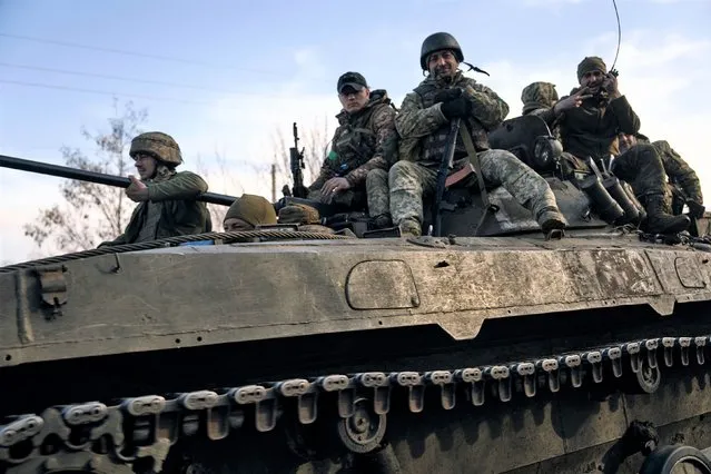 Ukrainian soldiers ride atop an APC on the frontline in Bakhmut, Donetsk region, Ukraine, Wednesday, March 22, 2023. (Photo by Libkos/AP Photo)