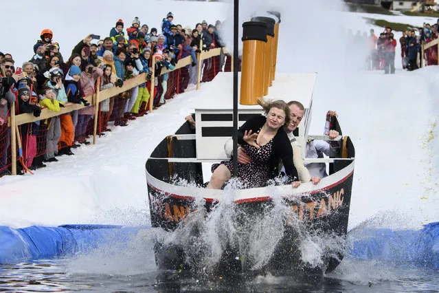 Dressed up contestants crash into the water on their decorated sledge as they take part in a waterslide competition, aiming to glide over the longest distance in a water pool dug in the snow of a ski slope, in Jaun, Switzerland, 19 February 2022. (Photo by Anthony Anex/EPA/EFE)