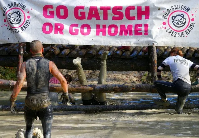 Competitors cross a water obstacle during the Wildsau Dirt Run (Wild Boar Dirt Run) obstacle course fun race at Hellsklamm ravine in Obertriesting, Austria, October 22, 2016. “Gatsch” reads “mud”. (Photo by Heinz-Peter Bader/Reuters)