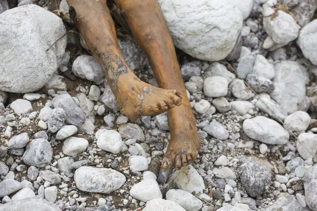 In this Tuesday, October 18, 2016 photo, an unclaimed body, victim of Hurricane Matthew, lies on the river bank of Bois Droit, in Port-a-Piment, a district of Les Cayes, Haiti. While relief can often be slow and chaotic in disasters all around the world, the Western Hemisphere’s poorest and least developed country is perennially beset by natural catastrophes and particularly ill-equipped to handle them. (Photo by Dieu Nalio Chery/AP Photo)