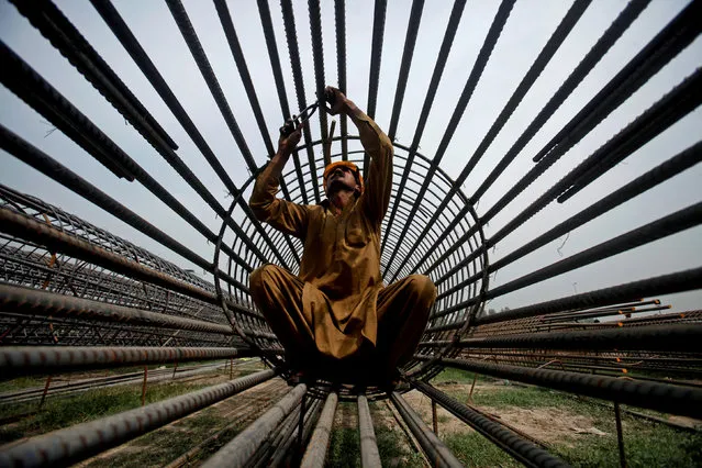 A worker ties steel bars at a construction site for a road in Peshawar, Pakistan March 27, 2018. (Photo by Fayaz Aziz/Reuters)