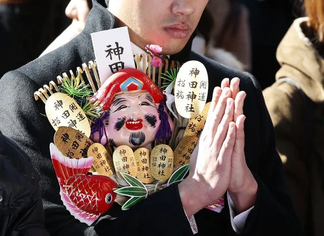 A man holding a rake, or kumade, decorated with imitation gold coins and other objects, offers a prayer at the start of the new business year at Kanda Myojin Shrine in Tokyo January 5, 2015. (Photo by Toru Hanai/Reuters)