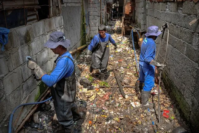 Workers walk on a creek clogged with plastic waste on April 15, 2023 in Caloocan, Metro Manila, Philippines. (Photo by Ezra Acayan/Getty Images)