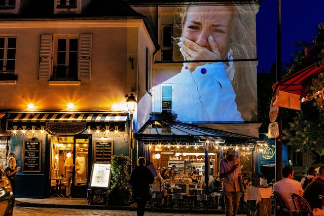 A photograph of Gold medalist Pauline Ferrand Prevot of Team France reacting on the podium during the Women’s Cross-Country Cycling Mountain Bike Gold Medal race at Elancourt Hill in Elancourt, France, is projected as part of Parisienne Projections in Montmartre on July 28, 2024 in Paris, France. Parisienne Projections displays the heroics and tragedies of 16 days of Olympic competition throughout the host city of Paris. (Photo by Carmen Mandato/Getty Images Europe)
