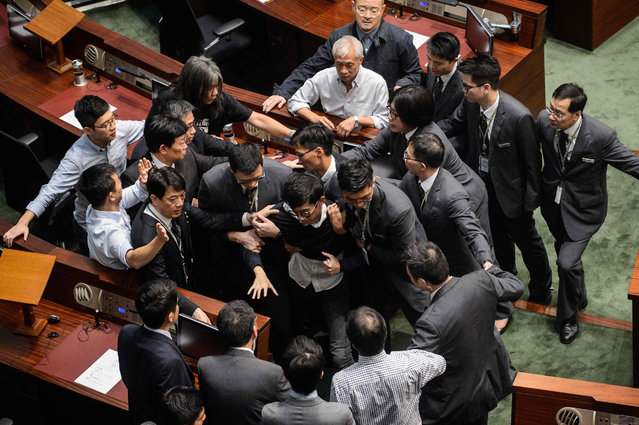 Newly elected lawmaker Baggio Leung (C) is restrained by security after attempting to read out his Legislative Council oath at Legco in Hong Kong on November 2, 2016. In the third consecutive week of chaos in the legislature, pro-independence lawmakers Baggio Leung and Yau Wai-ching entered the Legislative Council (Legco) on November 2 despite being banned from doing so, pending the result of a judicial review into whether they can take up their seats. (Photo by Anthony Wallace/AFP Photo)