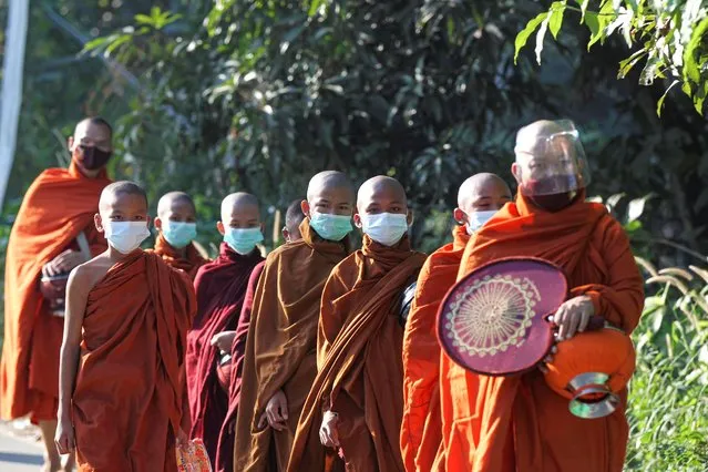 Buddhist monks wearing a face shield and masks to help curb the spread of the coronavirus walk to collect their morning alms from Buddhist devotees Thursday, December 10, 2020, on the outskirts of Yangon, Myanmar. (Photo by Thein Zaw/AP Photo)