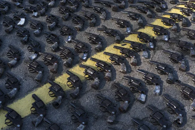 In this June 20, 2018 photo, revolvers that were confiscated in Rio State sit on the ground before being destroyed as part of the military intervention in Rio de Janeiro, Brazil. A portion of the around 8.500 weapons some seized during operations and others that people voluntarily delivered to the police were crushed with a Brazilian Army steam roller. (Photo by Leo Correa/AP Photo)