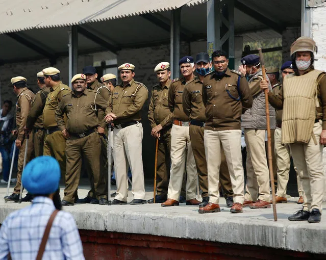 Policemen stand guard as farmers block railway tracks during a protest denouncing three farm laws approved by Parliament in September, in Sonepat, India, Thursday, February 18, 2021. (Photo by Manish Swarup/AP Photo)